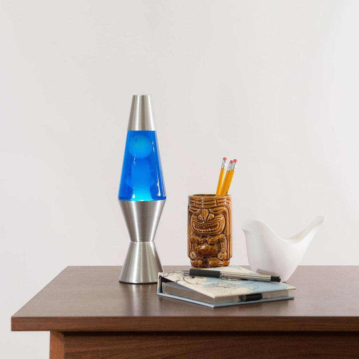 11.5” liquid motion® Lamp – White/Blue/Silver on table with notebook and tiki mug